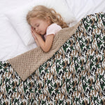 Child sleeping under a camouflage weighted blanket on a white bed