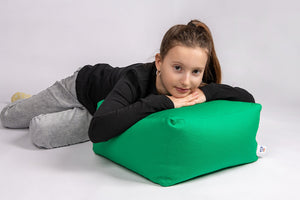 GIRL LEANING UPON GREEN COTTON SQUARE POUF