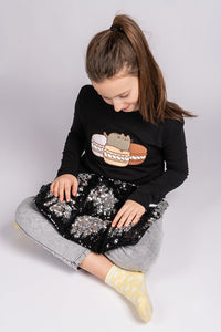 girl sitting with Two tone sequin weighted lap pillow in black and silver